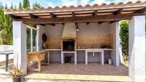 An outdoor kitchen with a tiled backsplash, a wooden table, and a hanging light fixture. - Villa Borras w/ private pool, 3km to beach! (El Vendrell)