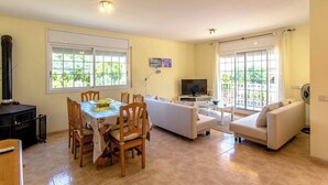 A living room with a dining table, two sofas, a TV, and a fireplace. - Villa Borras w/ private pool, 3km to beach! (El Vendrell)