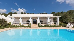 A modern villa with a swimming pool, featuring a covered patio with seating and a view of the pool. - Casa Murredda by Perle di Puglia (Ostuni)