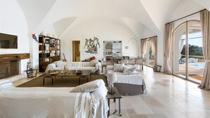 A spacious living area with a fireplace, a dining table, and a kitchen in the background. - Casa Murredda by Perle di Puglia (Ostuni)