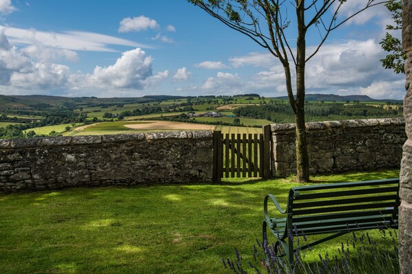 A stone wall with a wooden gate, a bench, and a view of a green landscape with hills and fields. - OVERTHWARTS FARMHOUSE five bedroom, nr. Alnwick. 9 miles from the coast (Alnwick)