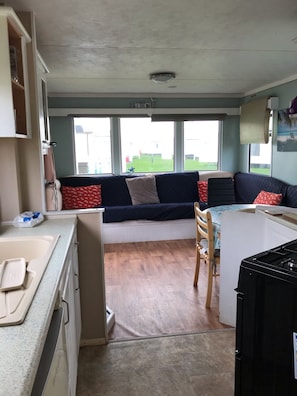 Cozy living space with a kitchenette, sofa, and large windows offering a view of the outdoors.