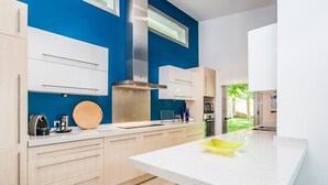 Une cuisine moderne avec des meubles de couleur bois clair, une hotte en acier inoxydable et un mur d’accent d’un bleu vif.