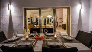 Une table à manger dressée avec des assiettes, des verres et des couverts, agrémentée d’une bougie et d’un élément décoratif central.