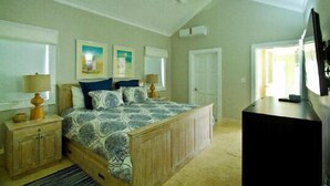 Quarto com cama, mesas de cabeceira, escrivaninha e televisão.