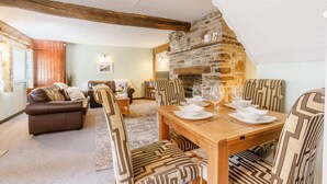 A cozy living room with a fireplace, a dining table set for four, and a comfortable sofa.