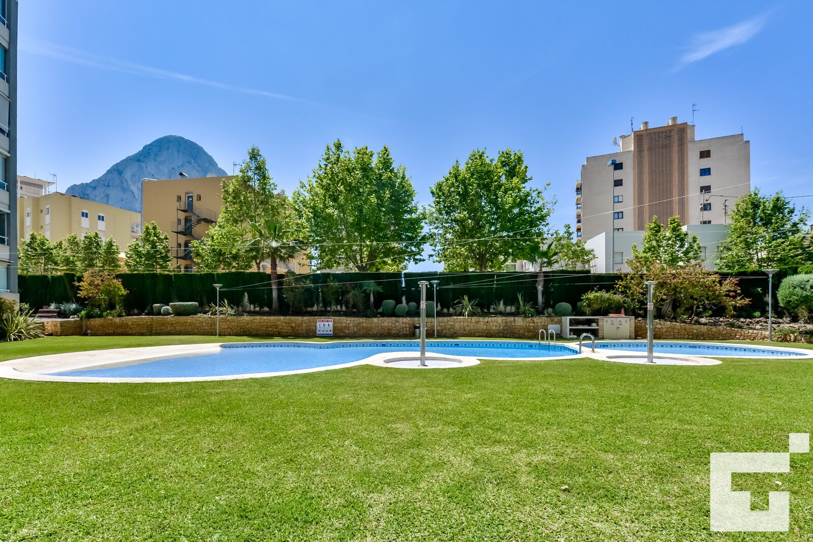 A pool area with a circular design, surrounded by well-maintained grass and trees.