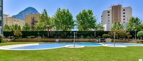 A pool area with a circular design, surrounded by well-maintained grass and trees.