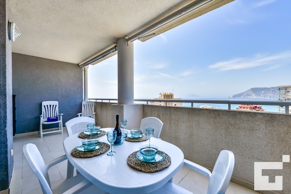 Un balcón con mesa para dos, sillas y vista al mar.