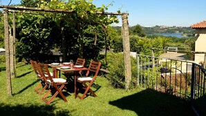 A table set outdoors with chairs, surrounded by greenery and a view of a lake.