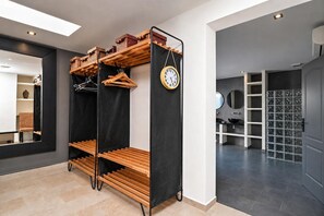 A modern interior with a black shelving unit, wooden shelves, and a clock.