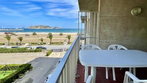Un balcón con vista a una playa, un estacionamiento y una isla distante.