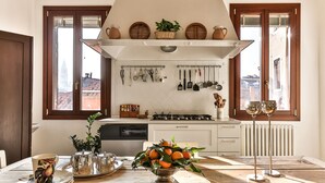 Une cuisine dotée d’un îlot central, de meubles blancs et d’une fenêtre donnant sur des immeubles.