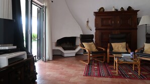 Un salon avec une cheminée, deux fauteuils, une table basse et un téléviseur.