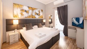 Un dormitorio moderno con una cama grande, lámparas de noche, un televisor de pantalla plana y obras de arte en la pared.