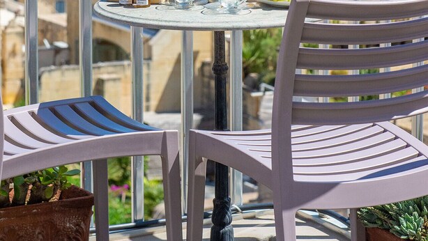 Un balcón con una mesa dispuesta para el desayuno, con vista a un paisaje urbano costero.