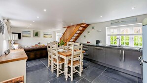 Een moderne keuken met een eethoek, een trap en uitzicht op groen.