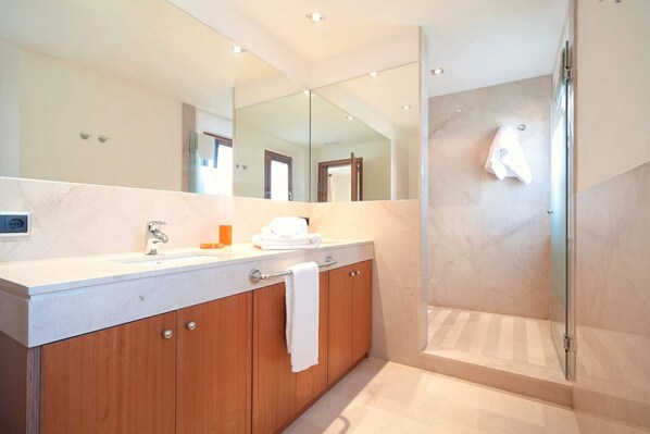 A modern bathroom with a large mirror, a sink, and a shower area.