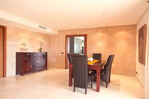 A spacious dining area with a wooden dining table and chairs, a dark wooden cabinet, and a vase of flowers.