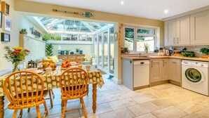 A kitchen with a dining area, a washing machine, and a large window. - 2 Bed in Appledore (oc-drum) (Appledore)