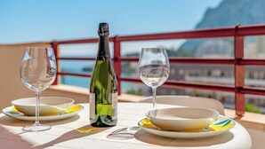 A table with a bottle and two glasses, a plate, and a view of the sea and a mountain. - Zafiro 35B - Grupo Turis - Calpe, Costa Blanca (Calpe)