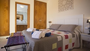 Un dormitorio con cama, mesita de noche, lámpara, espejo y puerta.