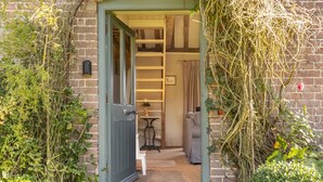 A brick building with a door leading to a room with a sofa and a table.