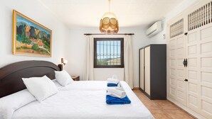 Ett hotellrum med en stor säng, en tavla på väggen, ett fönster med gardiner, en garderob och en luftkonditioneringsanläggning.