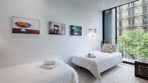 A hotel room with two beds, a large window with a view of buildings, and three artworks on the wall. - Pedrera - Habitat Apartments (Barcelona)