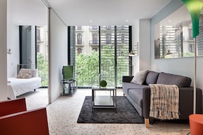 A modern living room with a sofa, a coffee table, and a bed. - Pedrera - Habitat Apartments (Barcelona)