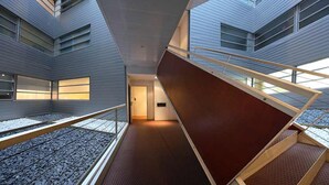 A modern interior with a central staircase, metal railings, and a patterned floor. - Pedrera - Habitat Apartments (Barcelona)
