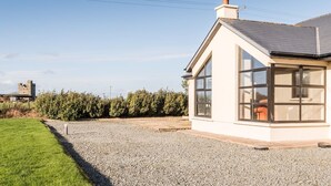 Een modern huis met een groot raam, een grindpad en een gazon.