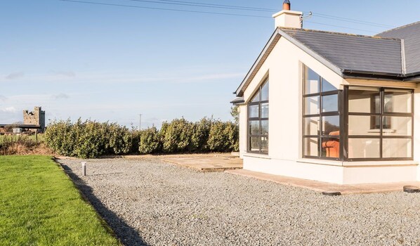 A modern house with a large window, a gravel driveway, and a grassy lawn.