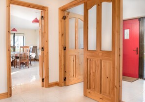 A wooden door with glass panels leading to a dining area with chairs and a table.