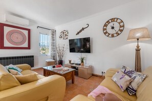 Un salon avec un canapé, une table basse, un téléviseur et une lampe.
