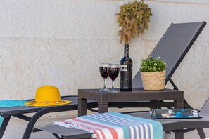 Uma área de estar com uma mesa posta, incluindo uma garrafa, copos, um chapéu e uma planta.