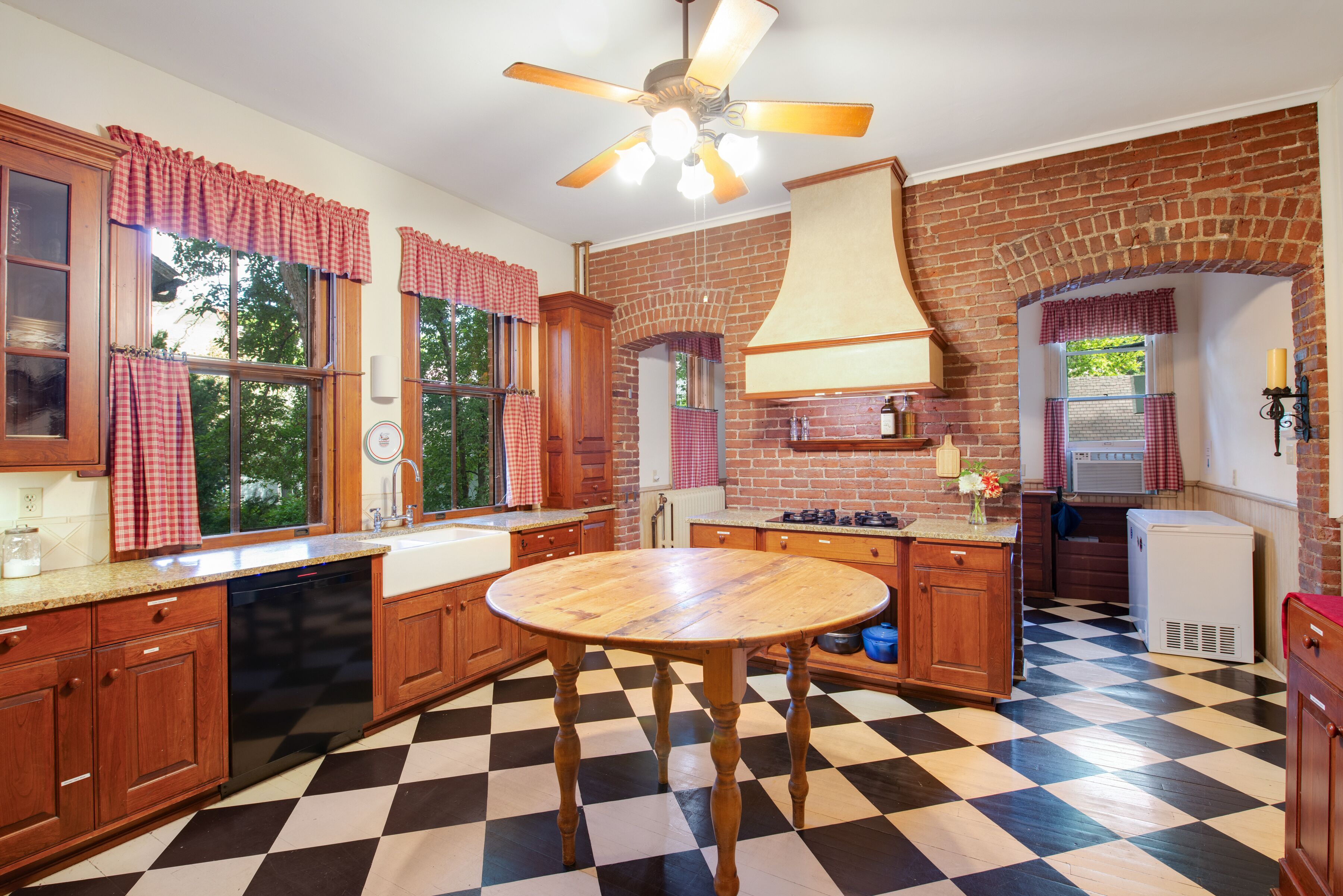 Une cuisine avec un carrelage à motifs, des meubles en bois, un îlot central et un ventilateur de plafond.