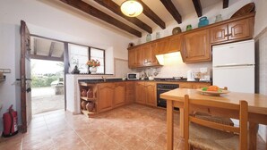 A kitchen with wooden cabinets, a tiled floor, a dining table with chairs, and a refrigerator. - Magnificent Memory Making - only 2km beach! (Palma de Mallorca)