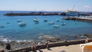 A coastal marina with several boats docked, a lighthouse, and a large ship named 'Fred Olsen'.