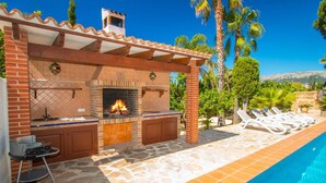 Una cocina exterior con chimenea de ladrillo, una barra y una parrilla.