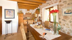 A dining area with a wooden table, wicker chairs, and a stone wall. - Pollensa retreat, walk to Old Town and 6km to beach! (Palma de Mallorca)