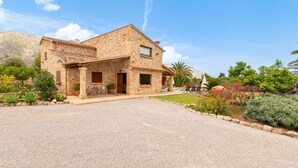 A stone house with a gravel driveway, surrounded by a garden with various plants and flowers. - Pollensa retreat, walk to Old Town and 6km to beach! (Palma de Mallorca)