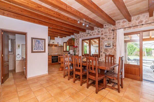 Un'ampia cucina con travi in legno, zona pranzo con un tavolo e sedie grandi, e una parete in pietra.