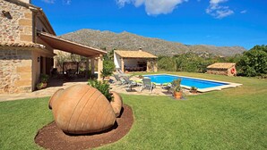 A stone house with a swimming pool, a large wooden barrel, and a mountain backdrop. - Pollensa retreat, walk to Old Town and 6km to beach! (Palma de Mallorca)