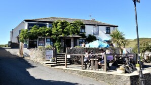 A traditional building with a stone facade, a signboard advertising breakfast service, and outdoor seating with umbrellas. - 2 Bed in Woolacombe (oc-beac4) (Woolacombe)