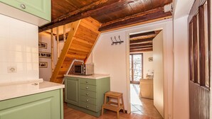 A kitchen with green cabinets, a wooden staircase, and a small wooden stool. - Little Vista, Smartno, Goriska Brda - 2 Bedroom Holiday House (Kojsko)