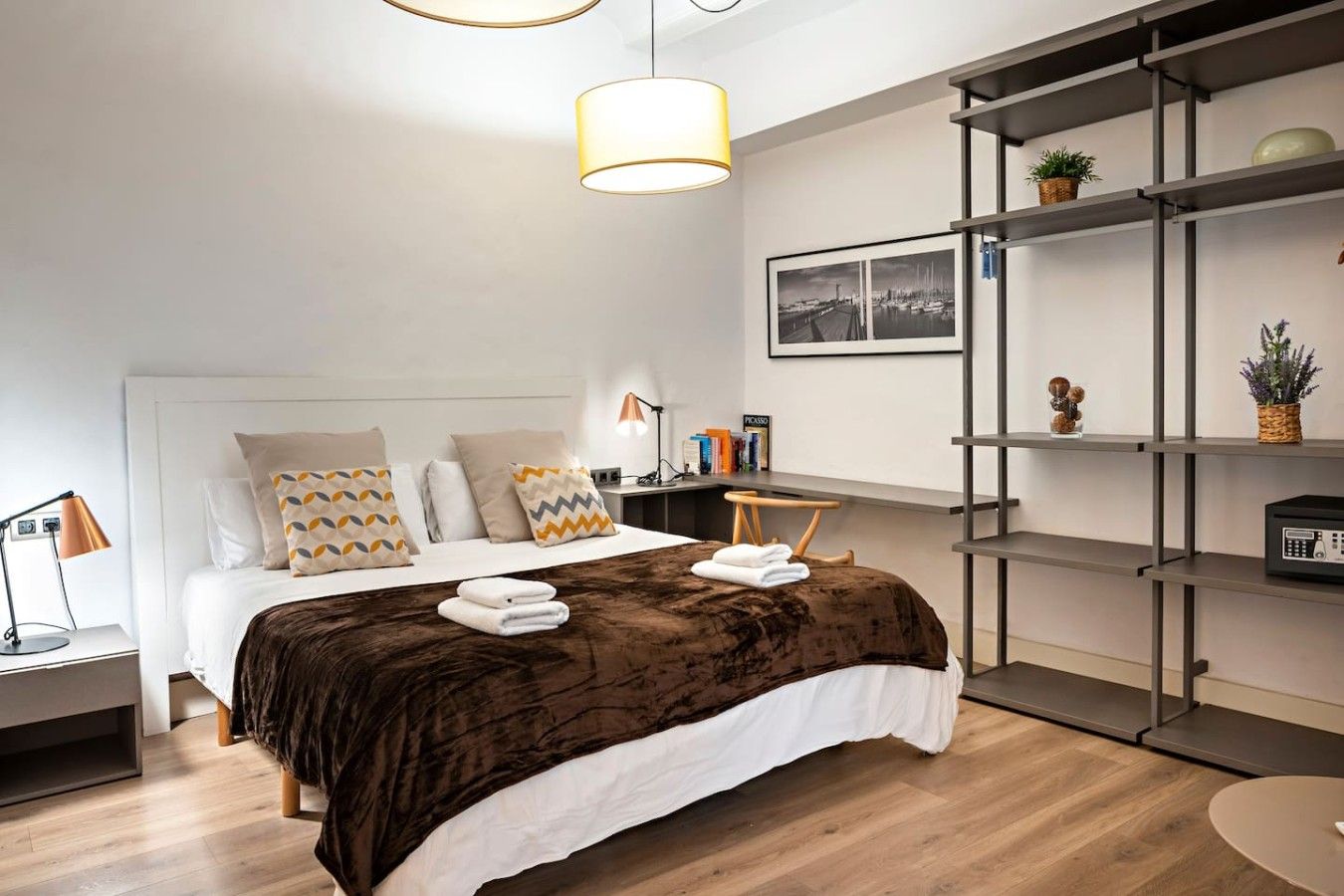 Une chambre d’hôtel moderne avec un grand lit, des tables de chevet, un bureau et une bibliothèque.