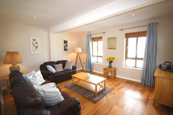 A living room with a sofa, coffee table, lamp, and artwork on the walls.