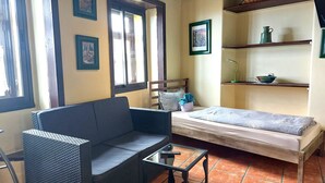 Une petite pièce agréable et confortable, avec un lit, un canapé, une petite table et une fenêtre.