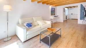 Un salon moderne avec un canapé blanc, une table basse en verre et un plafond en bois.